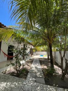a courtyard with a palm tree and a house at Praia, piscina e churrasco in Itamaracá