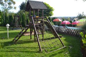 a playground with a slide in a yard with umbrellas at Katica Vendégház in Siófok