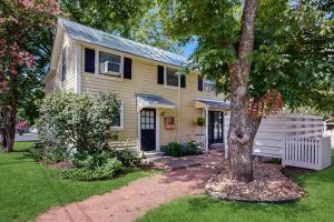 a yellow house with a tree in the yard at Cosmos Corner House in Fredericksburg