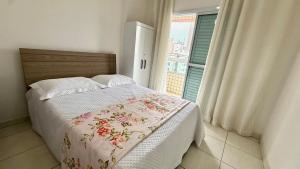 Un dormitorio con una cama con edredón floral y una ventana. en Residencial Maria Conceição, en Samaritá