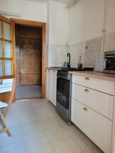 a kitchen with white cabinets and a stove top oven at La Mare Apartments - 25 in Constanţa