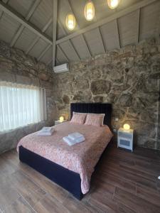 a bedroom with a large bed in a stone wall at Casa Vale do Luar in Celorico de Basto
