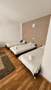 three beds in a room with wooden floors at Apartamente elegante in regim hotelier in Iaşi