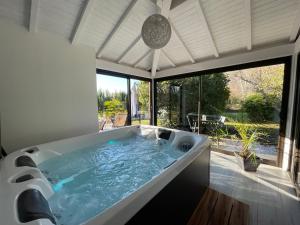 a large bath tub in a room with a large window at Villa KIKO, Gîte Spa & Sauna privatifs -5 min- Sarlat in Vitrac