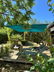 a patio with a blue umbrella on a deck at Villa KIKO, Gîte Spa & Sauna privatifs -5 min- Sarlat in Vitrac