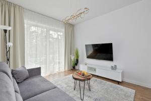 a living room with a couch and a flat screen tv at Sosnowa by Solarento in Mielno
