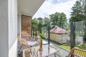 a balcony with chairs and a table with a view at Sosnowa by Solarento in Mielno