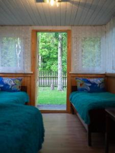 a bedroom with two beds and a window with a yard at Sodyba pas Babą - namas KLASIKA in Palanga