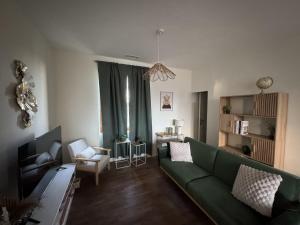 a living room with a green couch and a chair at La Villa Pagnon - 3 Chambres in Brive-la-Gaillarde