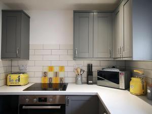 a kitchen with black cabinets and a microwave at Oak Barn in Porthtowan