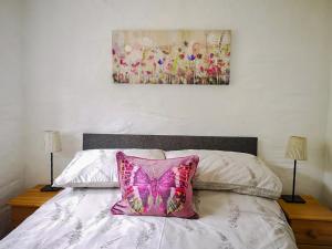 a pink butterfly pillow sitting on top of a bed at Oak Barn in Porthtowan +22 photos