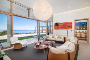 un soggiorno con mobili bianchi e ampie finestre di Spectacular Brac Villa Villa Adriatic 5 Bedrooms Stunning Sea Views & Infinity Pool & Private Gym Skrip a Supetar (San Pietro di Brazza)