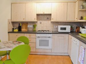 una cocina con electrodomésticos blancos y una mesa con sillas verdes en Bert's Cottage, en Fordingbridge