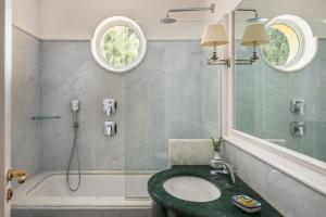a bathroom with a sink and a tub and a mirror at Hotel Caesar Augustus in Anacapri