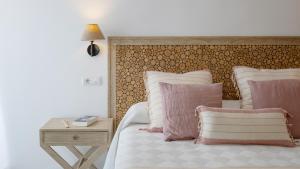 a bedroom with a bed with pink and white pillows at Hotel Rosamar - Emar Hotels in Es Pujols