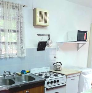 a kitchen with a white stove and a sink at Casa Chalet 6 personas in Cosquín +7 photos