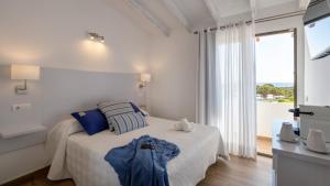 a white bedroom with a bed and a large window at Hotel Rosamar - Emar Hotels in Es Pujols