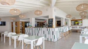 a restaurant with tables and chairs and a bar at Hotel Rosamar - Emar Hotels in Es Pujols