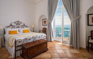 a bedroom with a bed and a balcony with the ocean at Hotel Caesar Augustus in Anacapri