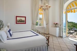 a bedroom with a large white bed and a balcony at Hotel Caesar Augustus in Anacapri