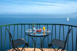 a table with a bowl of fruit on a balcony with the ocean at Hotel Caesar Augustus in Anacapri