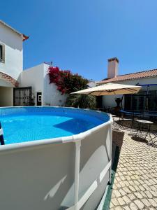 - une piscine avec un parasol en face d'une maison dans l'établissement Traditional Portuguese Village House - Casa Martins no 52, à Freiria