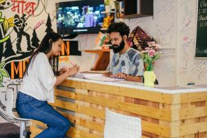 a man and a woman sitting at a counter at Urban Loft Hostel in Rishīkesh