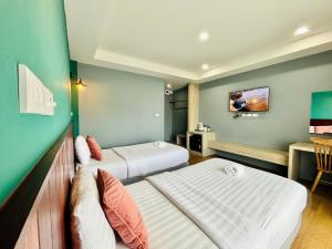 a hotel room with two beds and a tv at Pohnphansa Boutique Hotel in Narathiwat