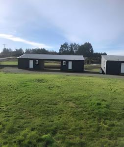 a building with a grass field in front of it at Lindas y acogedoras cabañas en puerto varas. in Puerto Chico