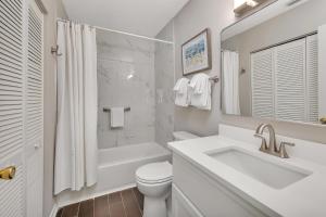 a white bathroom with a sink and a toilet at Shipwatch #305 in Saint Simons Island +24 photos