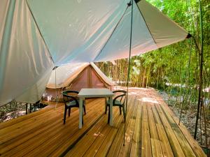 a table and chairs on a wooden deck with a tent at Camping les Avenières in Manthes