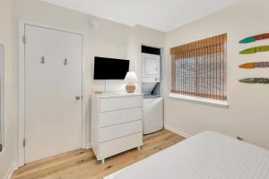 a white bedroom with a bed and a television at Shipwatch #311 in Saint Simons Island