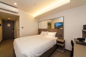 a bedroom with a large white bed and a mirror at Smile Hotel Hiroshima in Hiroshima