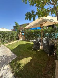 a yard with two chairs and an umbrella at Chalet rozza in El Alamein