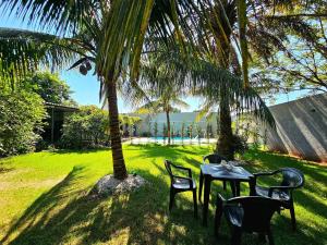 a table and chairs sitting under a palm tree at Casa 2 quartos 2 banheiros em meio a Área Verde in Foz do Iguaçu