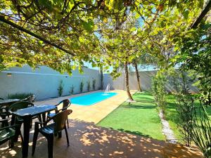 a patio with a table and chairs and a swimming pool at Casa 2 quartos 2 banheiros em meio a Área Verde in Foz do Iguaçu