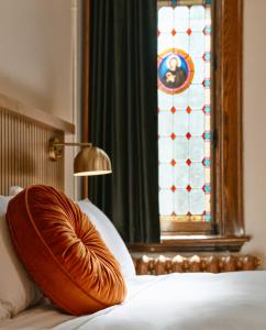 a bed with a pillow on it with a stained glass window at Hôtel Château Cran Chaud Chicoutimi in Saguenay +73 photos