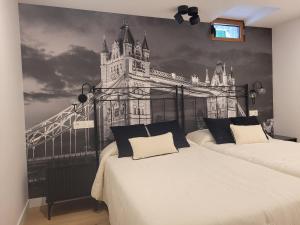 two beds in a room with a mural of a building at Llanesmar in Posada de Llanes