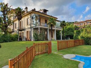 a house with a wooden fence in front of a yard at Mia Experience Lake Como in San Fermo della Battaglia