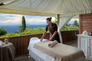 a woman making a bed in a room with a view at Hotel Caesar Augustus in Anacapri