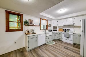 a large kitchen with white cabinets and a wooden floor at Riverfront Retreat with Near Boat Launch in Nineveh! 