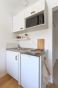 a kitchen with white cabinets and a microwave at Le studio de Gargantua in Dardilly +4 photos
