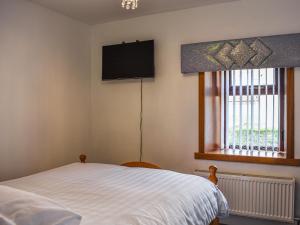 Un dormitorio con una cama y un televisor en la pared. en Belger Cottage, en Inverallochy 6 fotos más