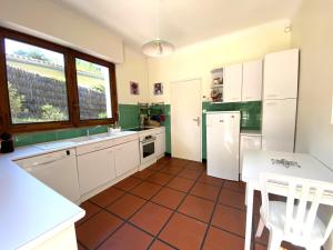 eine Küche mit weißen Schränken und einem Fliesenboden in der Unterkunft PINSONS maison familiale proche plage in Pyla-sur-Mer + 7 Fotos