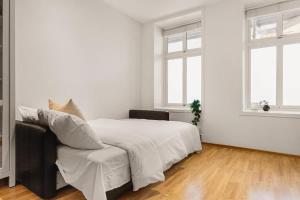 a white bedroom with a large bed and two windows at Dinbnb Apartments I 500m to Bryggen in Bergen