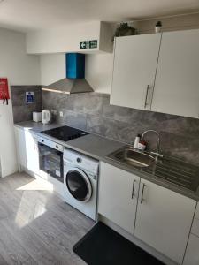 a kitchen with a washing machine and a sink at Luxurious ensuite rooms in Basildon