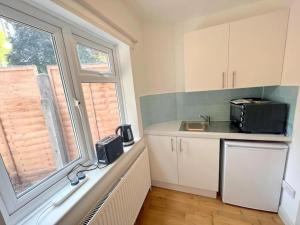 a kitchen with a counter and a window and a microwave at Studio (Twin) in Central Sutton in Cheam
