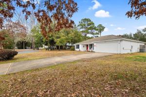 a house with a driveway in front of a yard at Sunnyside Retreat, Private pool, Bluewater Bay, Sleeps 11, Fenced Yard in Niceville