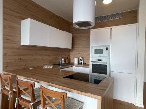 a kitchen with white cabinets and a wooden wall at SAG Sky park castle wiev Free parking Free wifi in Bratislava