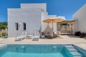 a swimming pool with two chairs and an umbrella at Villa Alma - Aliki Center in Aliki